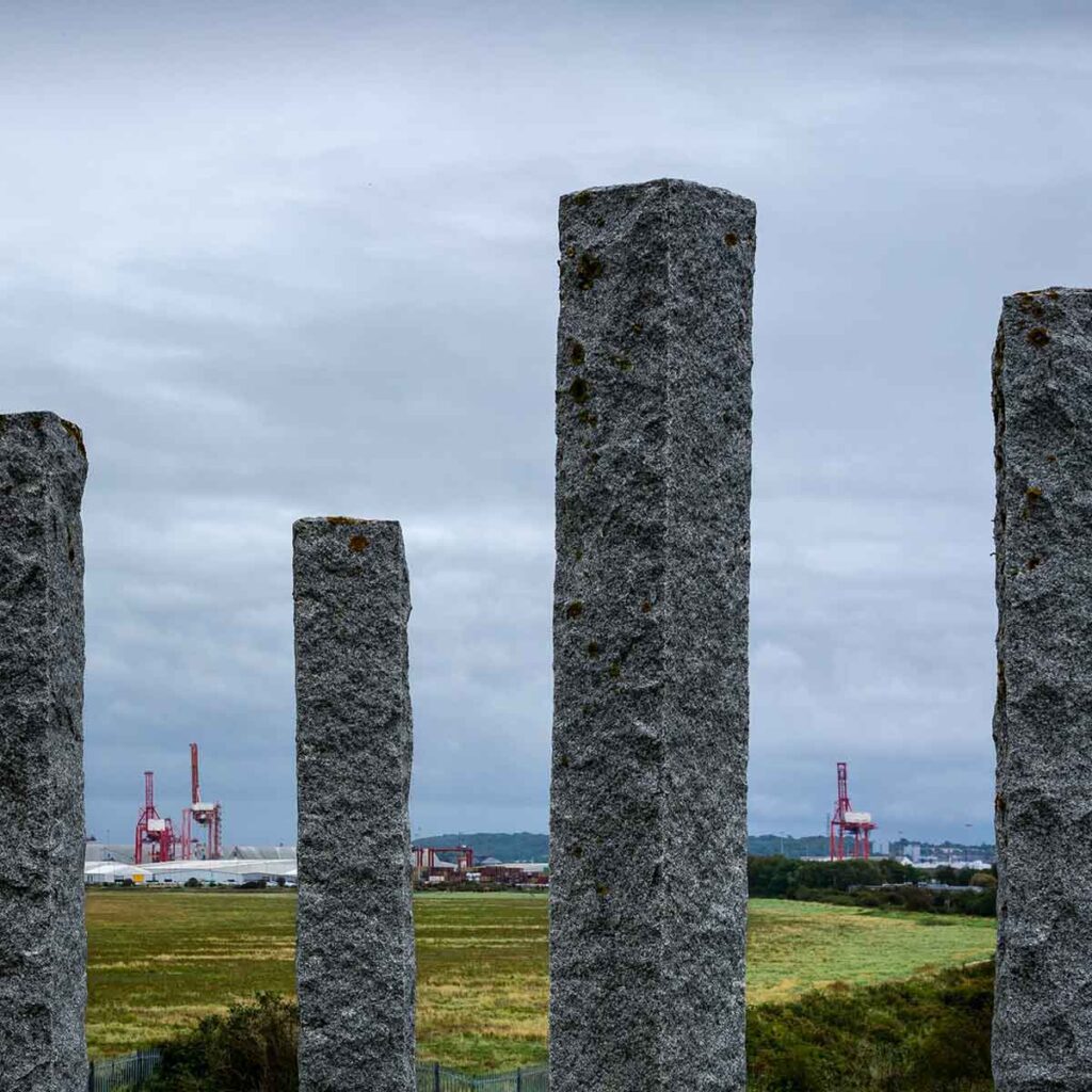 Bristol dock cranes viewed through the columns of the Full Fathom Five sculpture, by Michael Dan Archer, at Portishead.